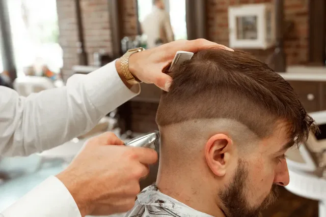 Profissional a atender um cliente durante um corte de cabelo