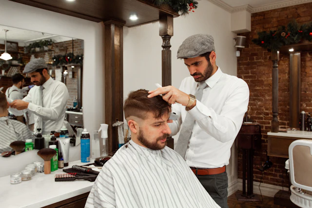 Barbeiro a cortar o cabelo de um cliente sentado na cadeira