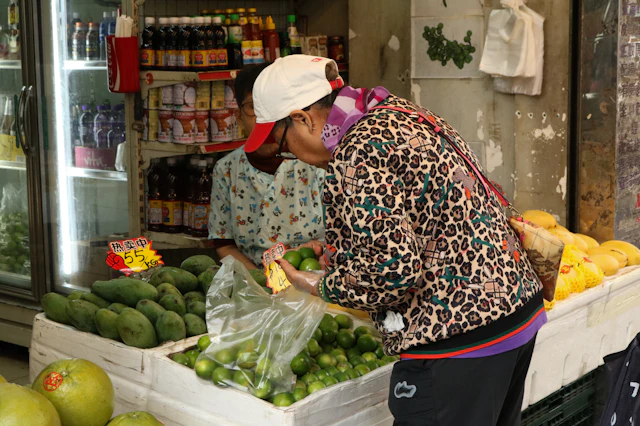 Pessoa a escolher legumes numa loja com caixas de produtos frescos